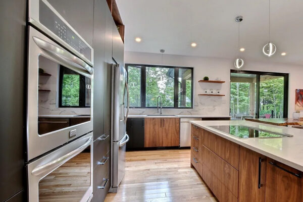 Cuisine moderne avec four, îlot et grandes fenêtres.