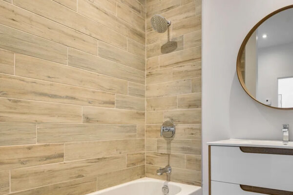 Salle de bain moderne avec baignoire blanche et miroir rond.