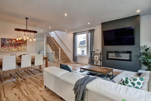 Salon moderne avec escalier et cheminée.