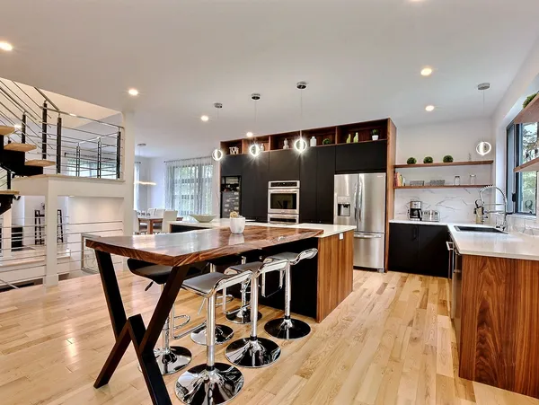 Cuisine moderne avec îlot central et luminaires suspendus.